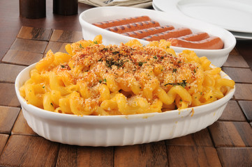 Serving dishes of macaroni and cheese and hot dogs