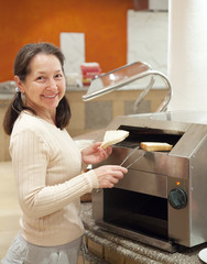 Fototapeta na wymiar woman makes toast in toaster