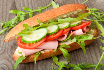 Sandwich with ham, tomato, cucumber and arugula 