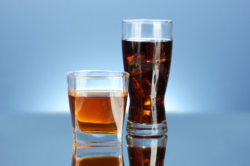 glass of whiskey and a glass of cola on blue background