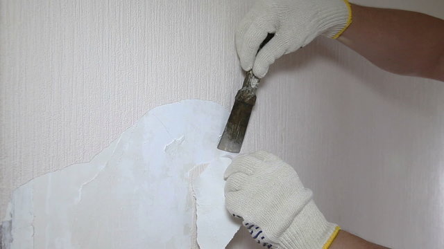 Man removing old wallpaper with the tool