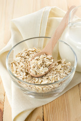 Oat flakes on a glass boel and jug of milk