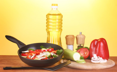 frying pan with vegetables on yellow background