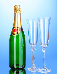 Bottle of champagne and goblets on blue background