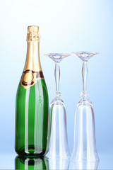 Bottle of champagne and goblets on blue background