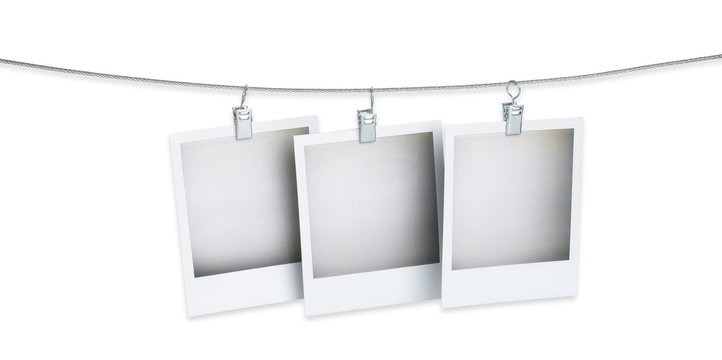 three blank polaroid pictures hanging on a wire isolated on whit