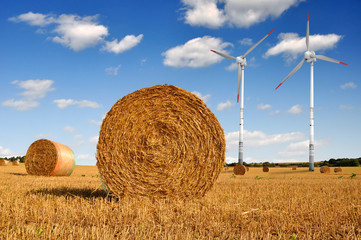Straw bales on farmland with wind turbine