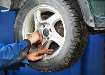 mechanic installing car wheel at service station