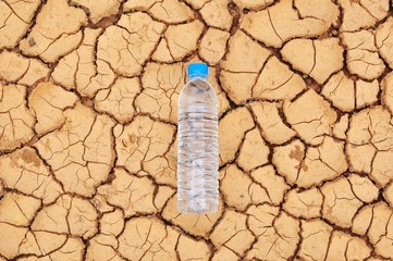A water bottle on dry and cracked ground