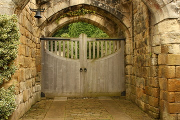 old wooden gate under sandstone arches