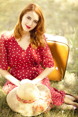 Redhead girl with suitcase at outdoor.