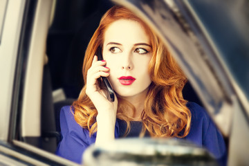 Fototapeta na wymiar Beautiful redhead businesswoman calling by phone in the car.