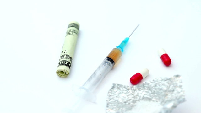 Pills cocaine and a syringe spinning