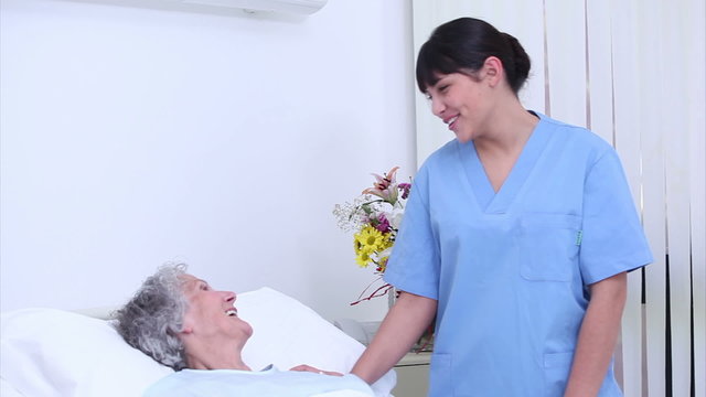 Nurse talking to a senior woman in her bed