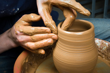 hands of a potter, creating an earthen jar on the circle