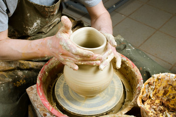 hands of a potter, creating an earthen jar of white clay