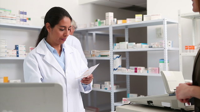 Smiling pharmacist handing paper to a customer