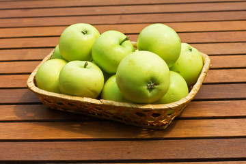 Set of fresh green apples in bucket on wooden background
