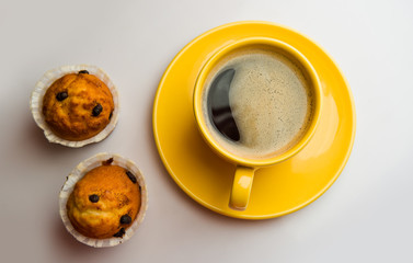 Coffee in an yellow cup and muffins