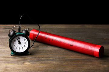 Dynamite with timer on wooden table on black background