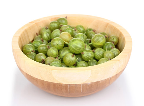 Green gooseberry in wooden bowl isolated on white