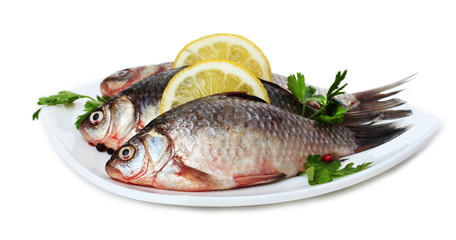 Fresh fishes with lemon and parsley on plate isolated on white