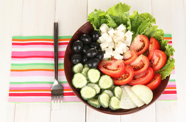 tasty Greek salad on white wooden background