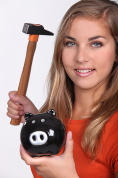 Young woman smashing her piggy bank