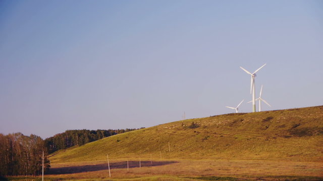 Wind turbines generating electricity near the forest