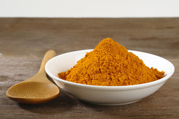 turmeric powder in white dish on wooden