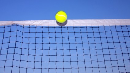 Close-up of a tennis ball touching the net tape