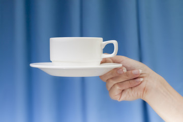 White cup in his hands on blue background