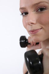 Closeup of a young woman using dumbbells