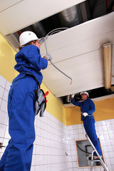 Two electrician repairing ceiling lighting