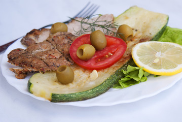 Appetizing fried meat with vegetables and olives