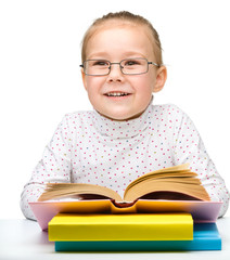Cute cheerful little girl reading book