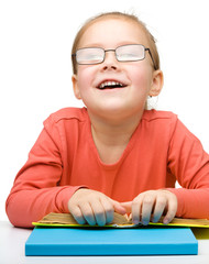 Cute cheerful little girl reading book