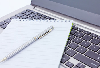 notebook and pen lie on the keyboard