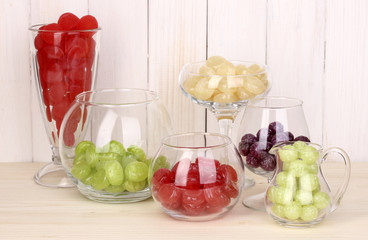 Color candies in glasses on wooden background