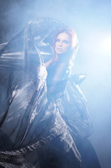 Fashion shoot of a young redhead woman in a mystique dress