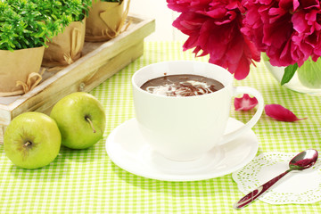 cup hot chocolate, apples and flowers on table in cafe