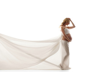 Fototapeta na wymiar A young blond pregnant woman in white silk clothes