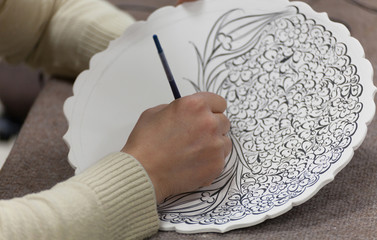 artisan drawing flower figure on blank plate
