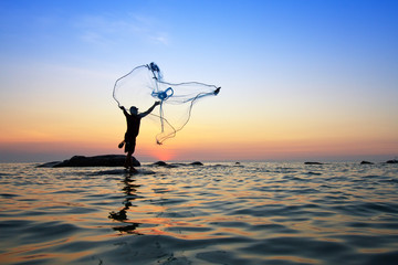 throwing fishing net during sunrise, Thailand