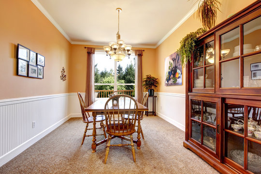 Peach dining room with beige carpet with white border.