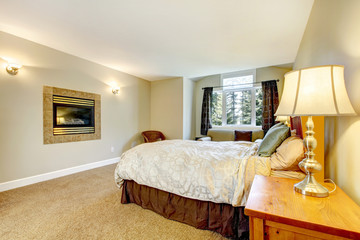 Large bedroom with fireplace and nightstand with lamp.