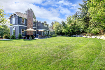 Blue large house with backyard and green landscape. © Iriana Shiyan