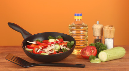 frying pan with vegetables on red background