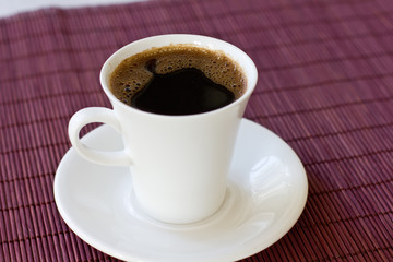 Wonderful white cup with hot black coffee on wooden background