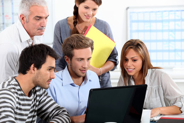 Informal team of people sitting round a laptop computer